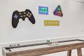 A room with a neon sign reading "GAME ROOM" and another sign saying "GAMER AT WORK". There's also a "NO SKATEBOARD" sign. - Quiet Pet-Friendly Spot Near It All! (Franklin)