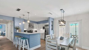Une cuisine moderne avec des meubles blancs, des touches de bleu et un îlot central doté de tabourets.