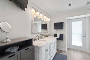 Une salle de bain moderne avec un meuble-lavabo double, un grand miroir et un téléviseur fixé au-dessus du lavabo.