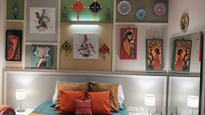 A hotel room with a bed, pillows, and wall decorations including framed art and plates.