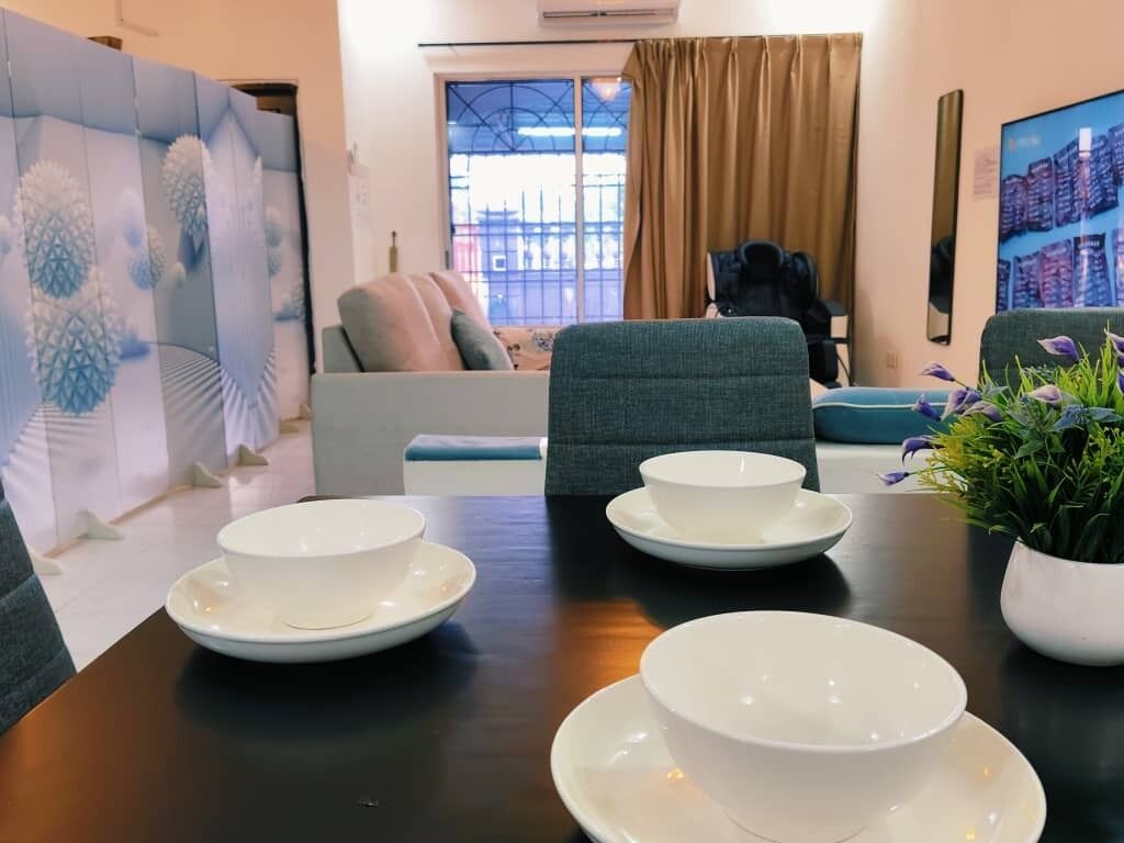 A dining area with a table set for four, a sofa, and a potted plant.
