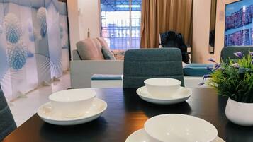 A dining area with a table set for four, a sofa, and a potted plant.