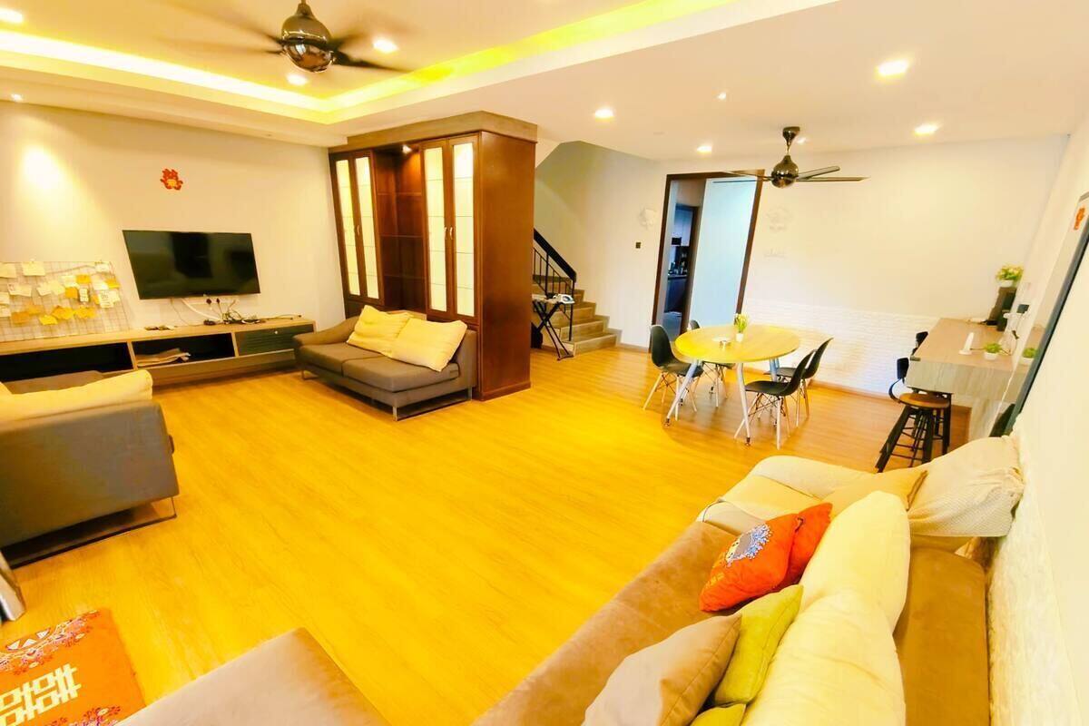 A modern living room with a sofa, a TV, and a staircase leading to another level.