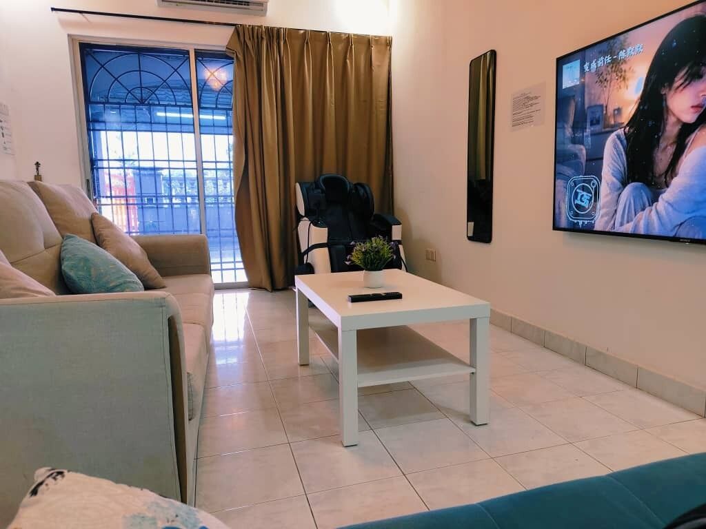 A living room with a sofa, a coffee table, a TV, and a window with curtains.