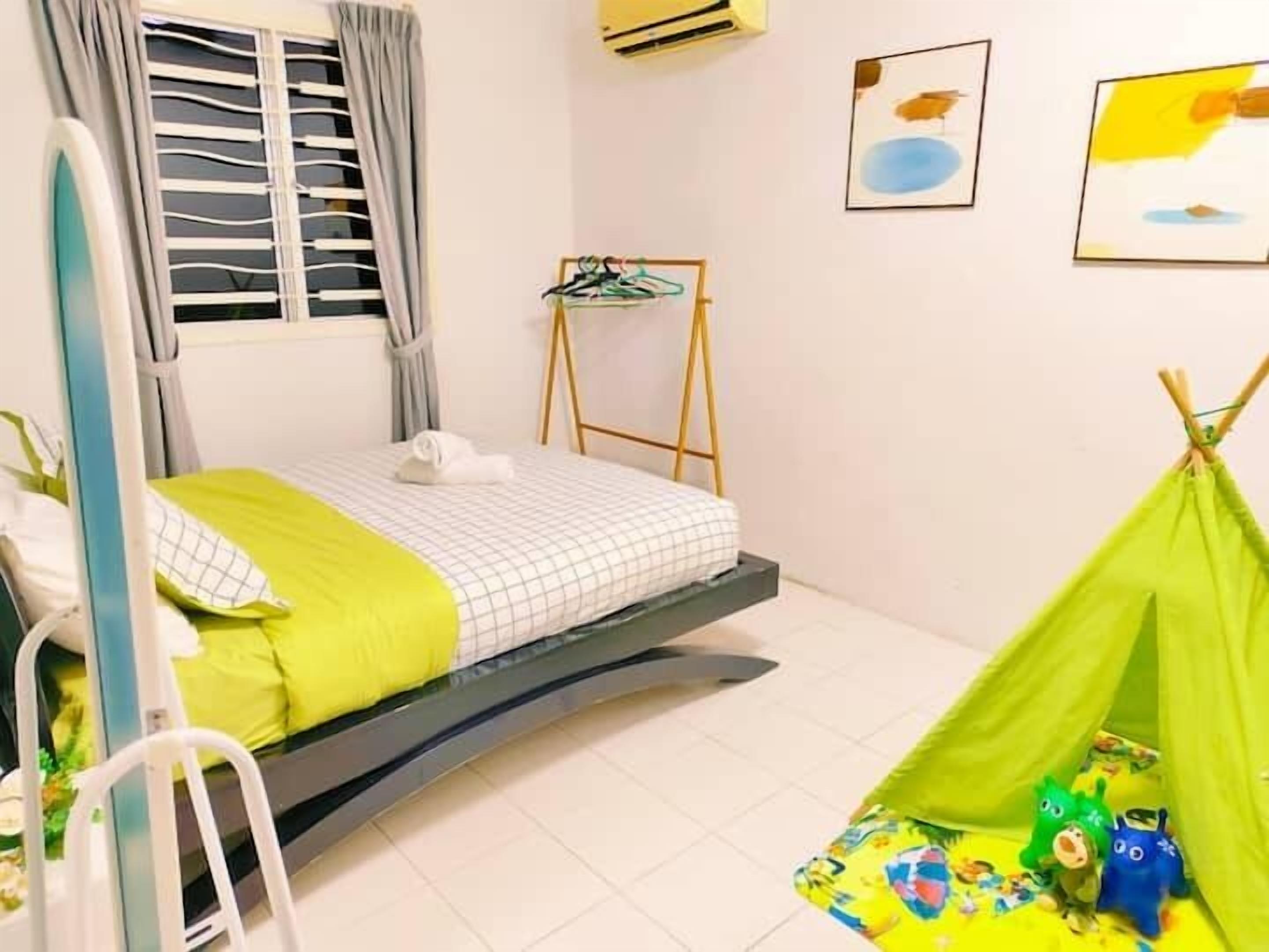 Una habitación con una cama, una ventana con cortinas, un aire acondicionado de pared y una tienda verde con juguetes.