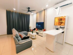 Uma sala de estar moderna com sofá, mesa de centro, televisão e uma pequena cozinha.