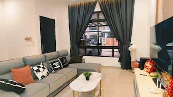 A modern living room with a grey sofa, a small round table, and a TV.