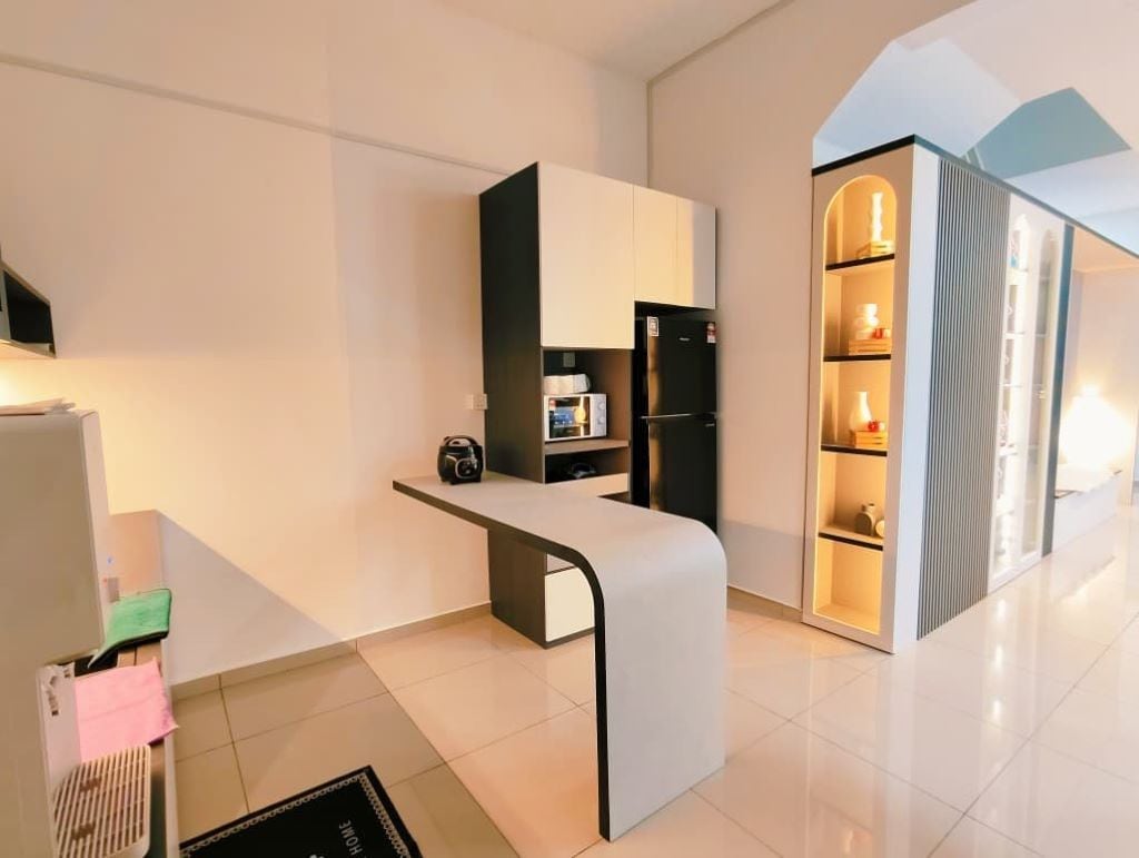 Una cocina moderna con refrigerador incorporado, encimera y una pequeña zona de estar.
