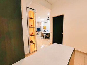 A modern interior with a white table, a kitchen area, and a dining space. - ioic (Kulai)