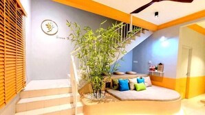 A staircase leading to a living area with a sofa and cushions, a bamboo plant, and a ceiling fan. - ioic (Kulai)