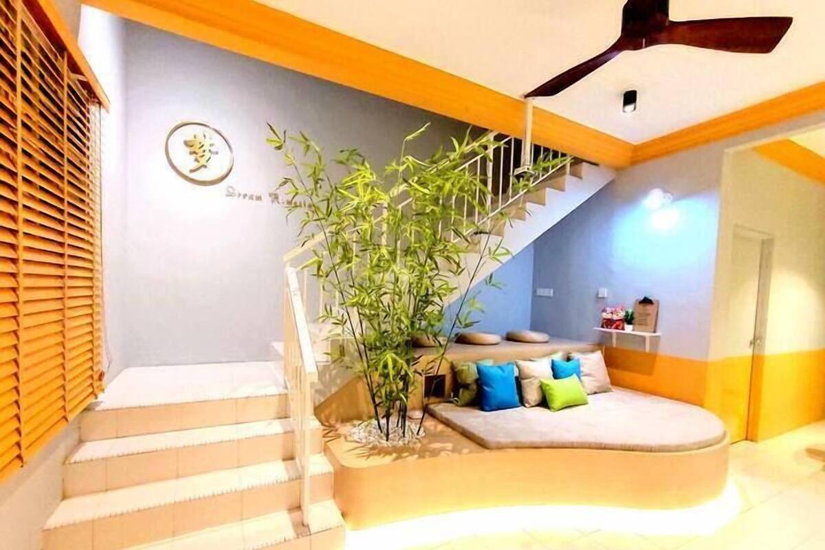A staircase leading to a living area with a sofa and cushions, a bamboo plant, and a ceiling fan.