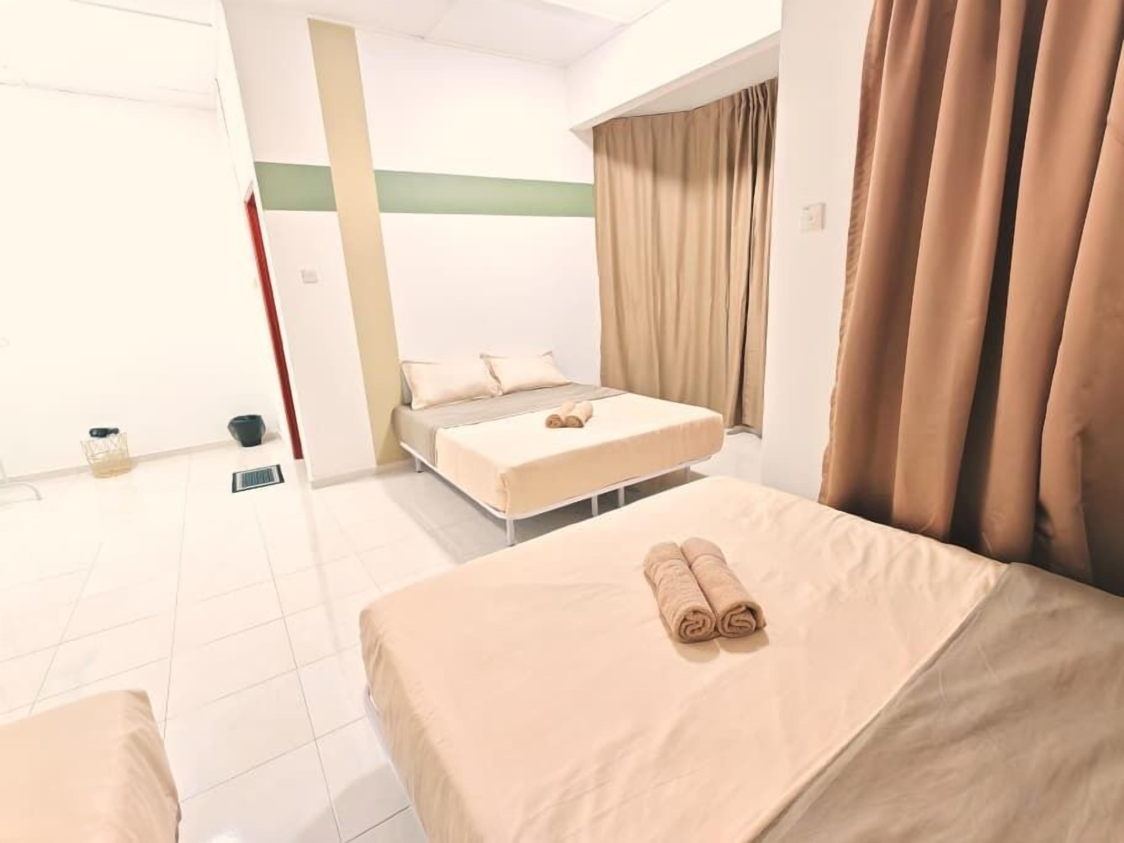 A hotel room with a bed, a bench, a small table, and a window with curtains.