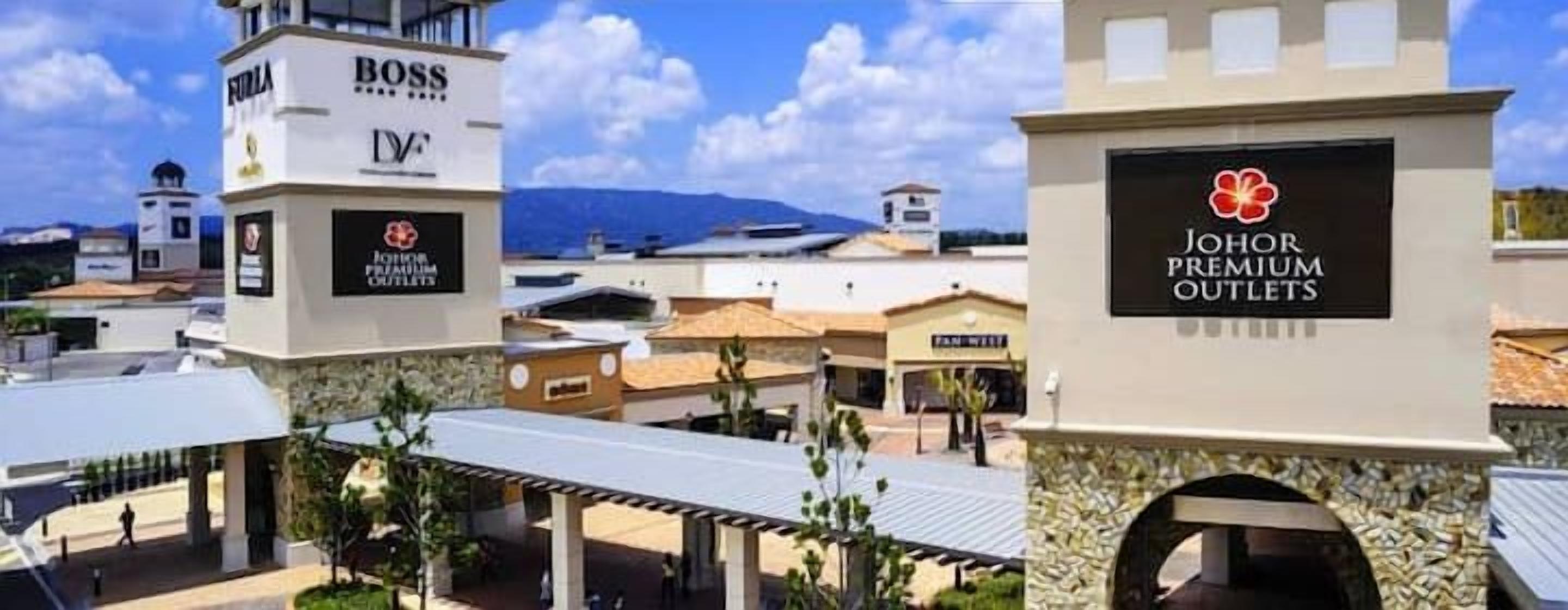 A commercial area with multiple buildings, including a structure labeled "Johor Premium Outlets" and another with "Boss" signage.