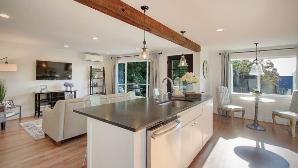 A modern kitchen with a central island, built-in appliances, and a dining area with a view. - Chic & Comfy Upper 2B @DT Kirkland | Walk to Lake (Kirkland)