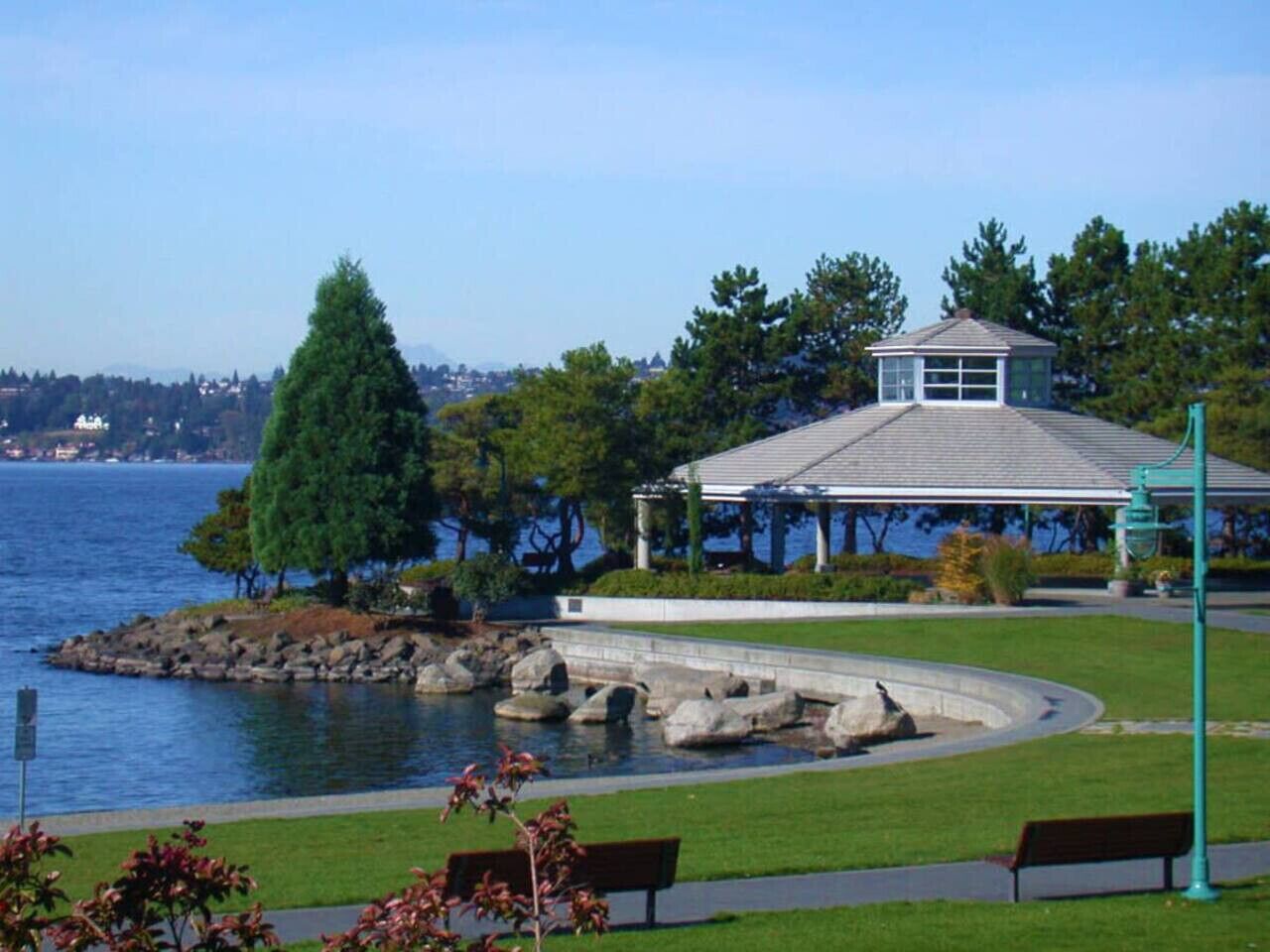 A waterfront park with a gazebo, benches, and a curved pathway.