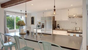 A modern kitchen with a large island, stainless steel appliances, and pendant lighting. - Chic & Comfy Upper 2B @DT Kirkland | Walk to Lake (Kirkland)
