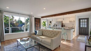 A modern living room with a sofa, coffee table, and large windows. - Chic & Comfy Upper 2B @DT Kirkland | Walk to Lake (Kirkland)