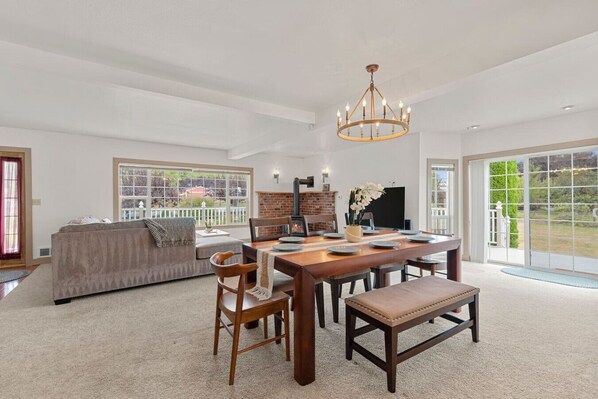 A spacious living room with a large dining table, a sofa, and a fireplace.