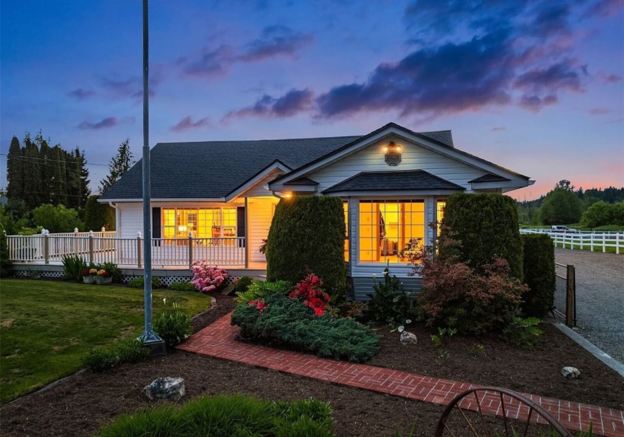 A two-story house with a porch, a well-maintained garden, and a clear sky at dusk.