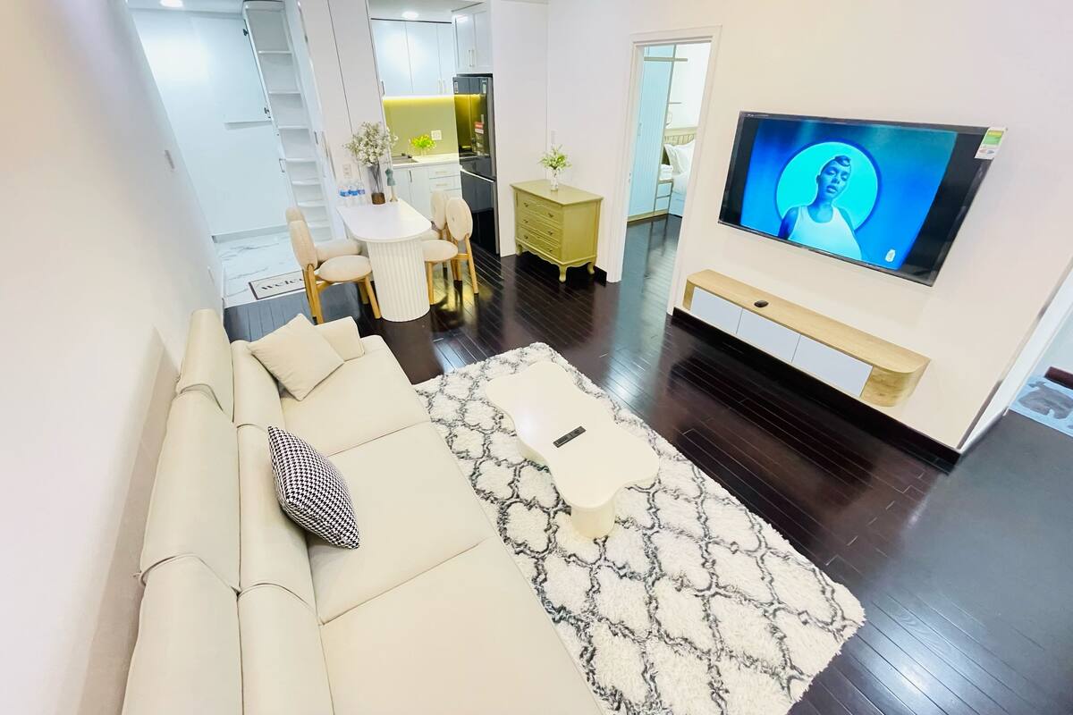 Een moderne woonkamer met een bank, televisie en een eethoek met tafel en stoelen.