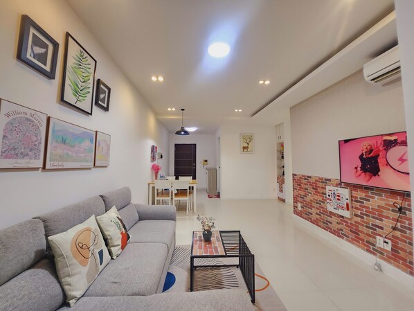 Una sala de estar moderna con un sofá gris, una mesa de centro y obras de arte enmarcadas en las paredes.
