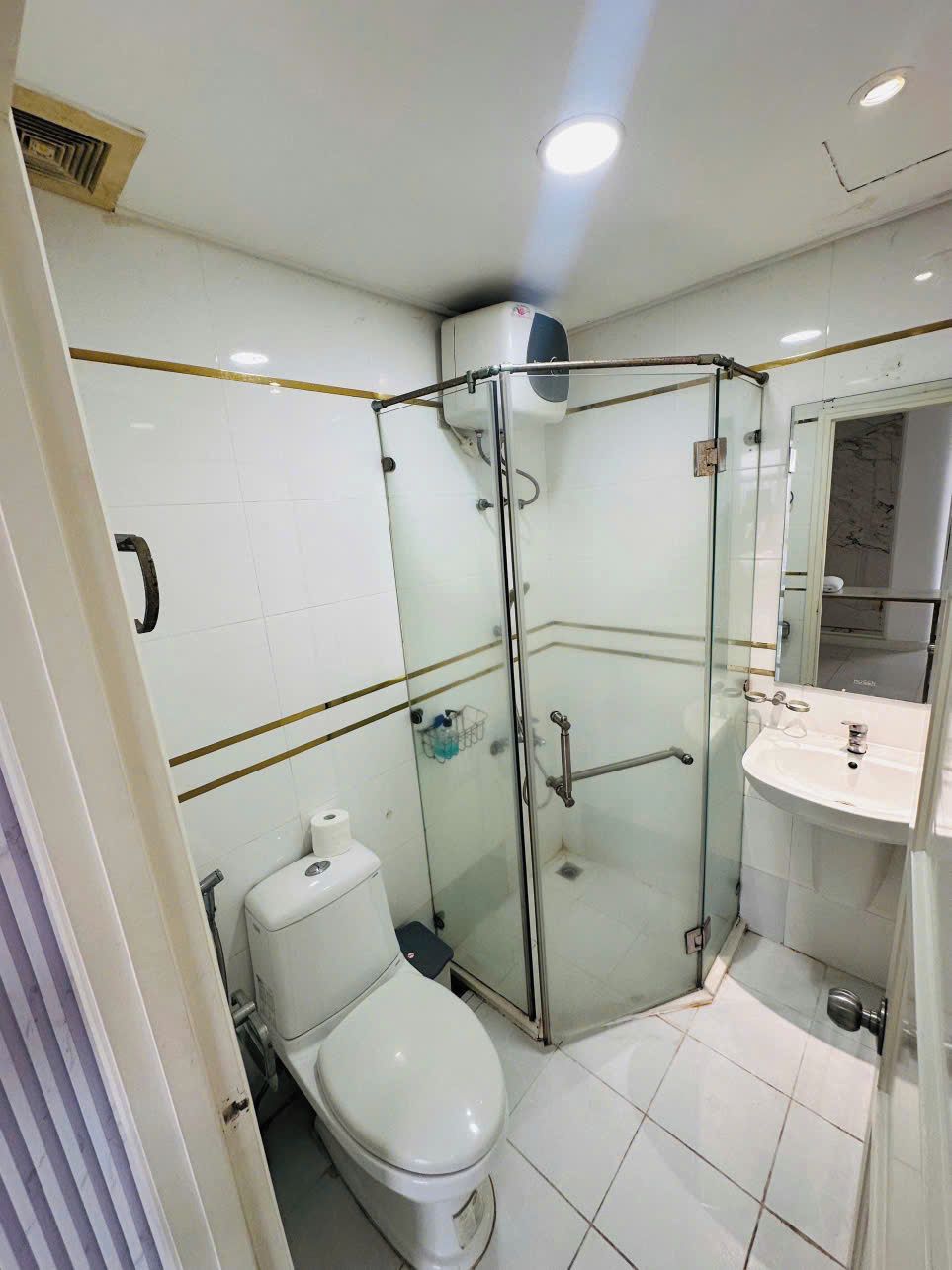 A small, modern bathroom with a glass shower enclosure, a toilet, and a sink.