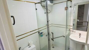 A small, modern bathroom with a glass shower enclosure, a toilet, and a sink.