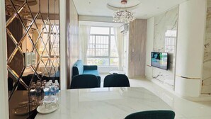 A modern dining area with a white table, dark chairs, and a TV on the wall. - Sky Garden 3 (Ho Chi Minh City)