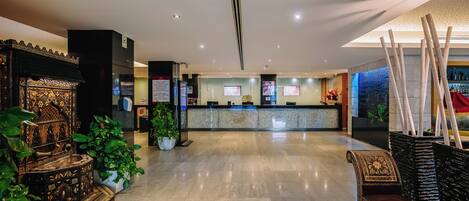 Eine Hotellobby mit einer Rezeption, einem dekorativen Brunnen und einer Sitzecke.