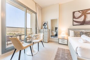 A modern hotel room with a balcony, a dining area, a bed, and a large abstract painting.