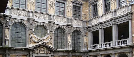 A historic building with classical architecture, featuring arched windows, detailed stone carvings, and a central courtyard.