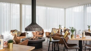 A modern living room with a central fireplace, leather sofas, a round coffee table, and a dining area with a wooden table and chairs. - Best Place to Stay in Antwerp! 2 Larges Units Close to The Beguinage! (Antwerpen)