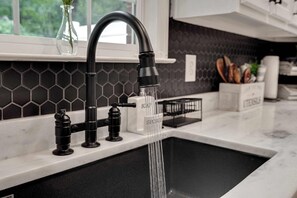 A kitchen with a black faucet, a soap dispenser, and a sponge holder on the countertop. - The Daisy Den * 20mins to Downtown Chatt * Mins to Blue Hole * (Soddy-Daisy)