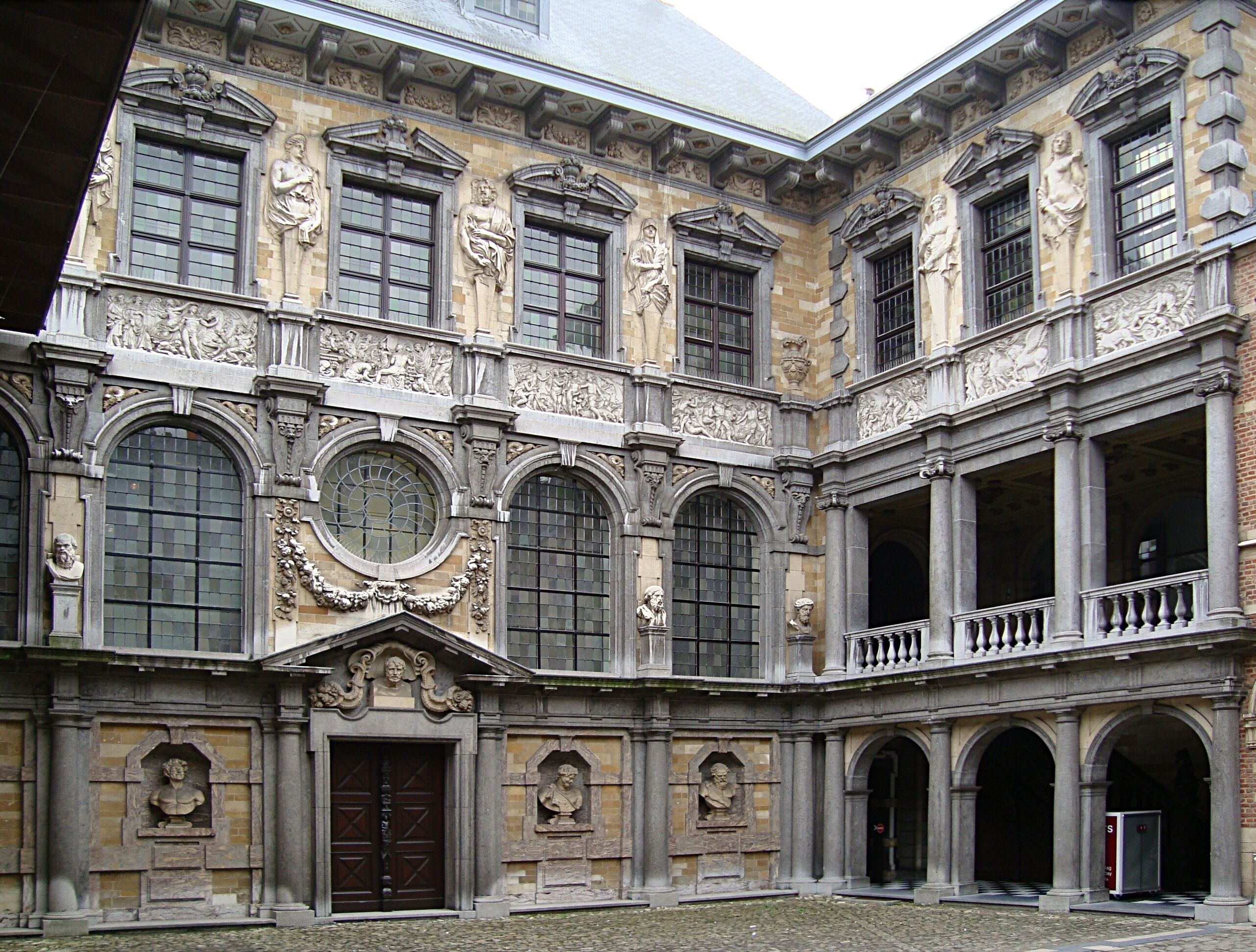 A historic building with classical architecture, featuring arched windows, detailed stone carvings, and a central courtyard.