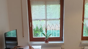 A room with a wooden table, a bench, a radiator, and a window with a view of greenery. - Beautiful vacation apartment for fitters (Bärnau)