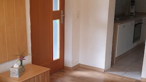 A bedroom with a bed, a wooden cabinet, a small table with a vase, and a door leading to a kitchen. - Beautiful vacation apartment for fitters (Bärnau)