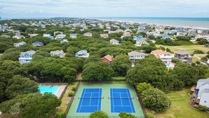 An aerial view of a residential area with two tennis courts surrounded by lush greenery and houses. - Duck Condo, 5 min walk to beach w/ community pool! (Duck)