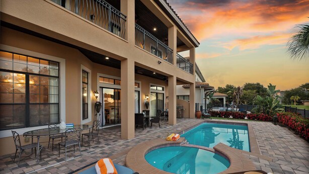 A hotel with a pool, outdoor seating, and a balcony. - Spacious villa near Disney w/ pool & cinema (Kissimmee)