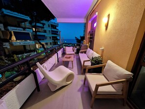 Un balcon avec vue sur la mer, aménagé avec un canapé, des fauteuils et une table.