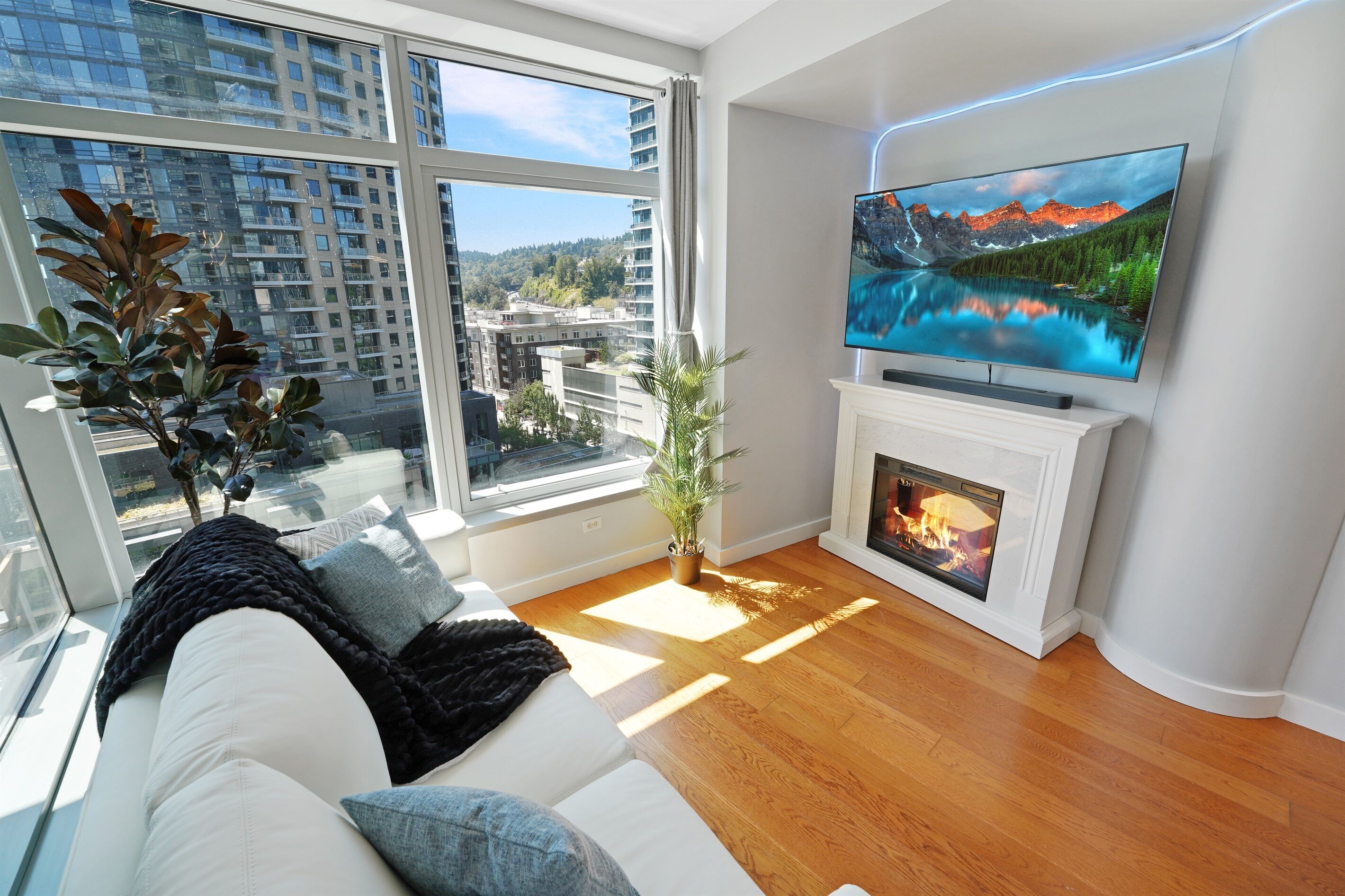 A modern living room with a large window, a fireplace, and a flat-screen TV.