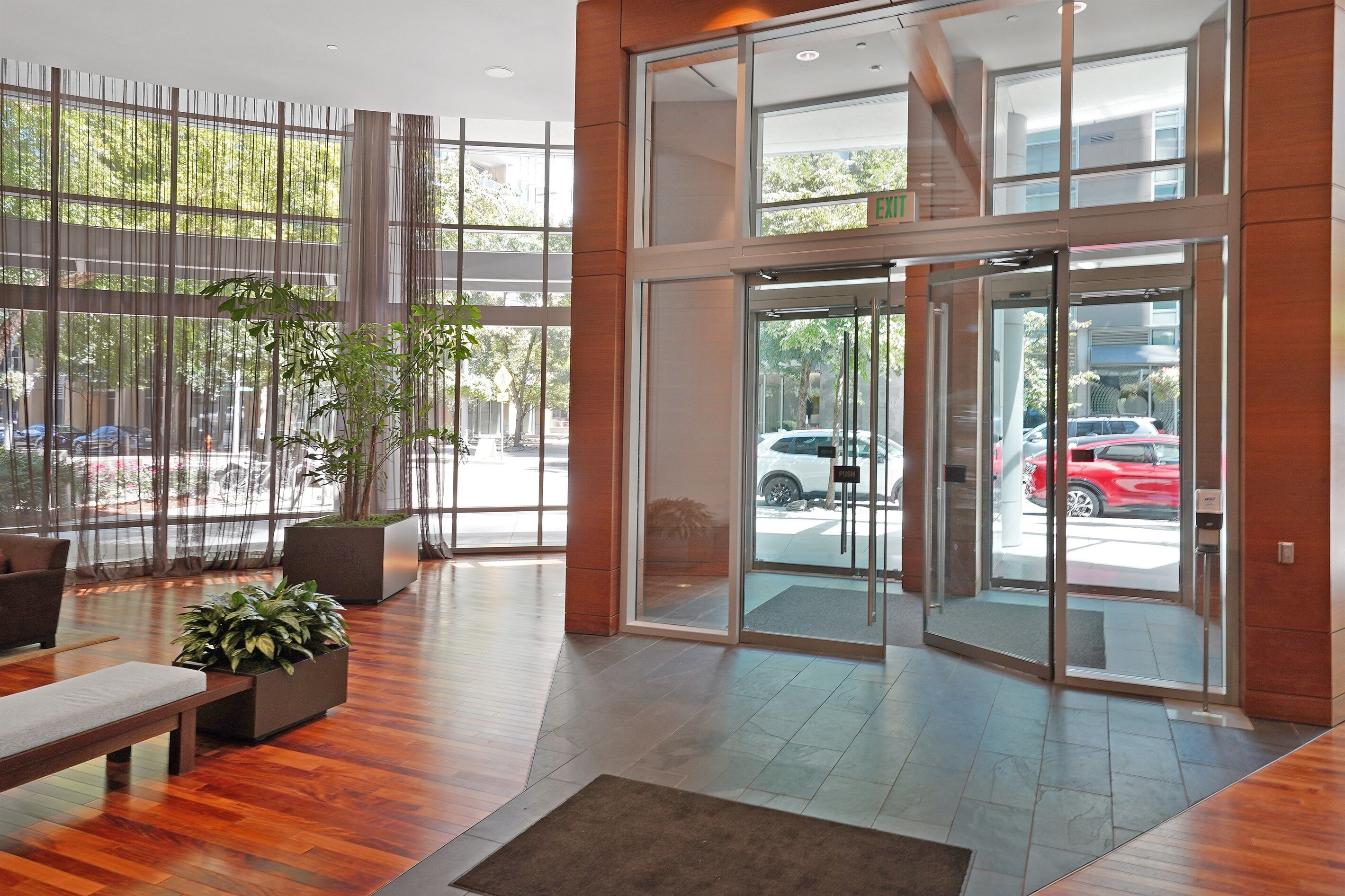 A modern lobby with a wooden floor, large windows, and a glass entrance.