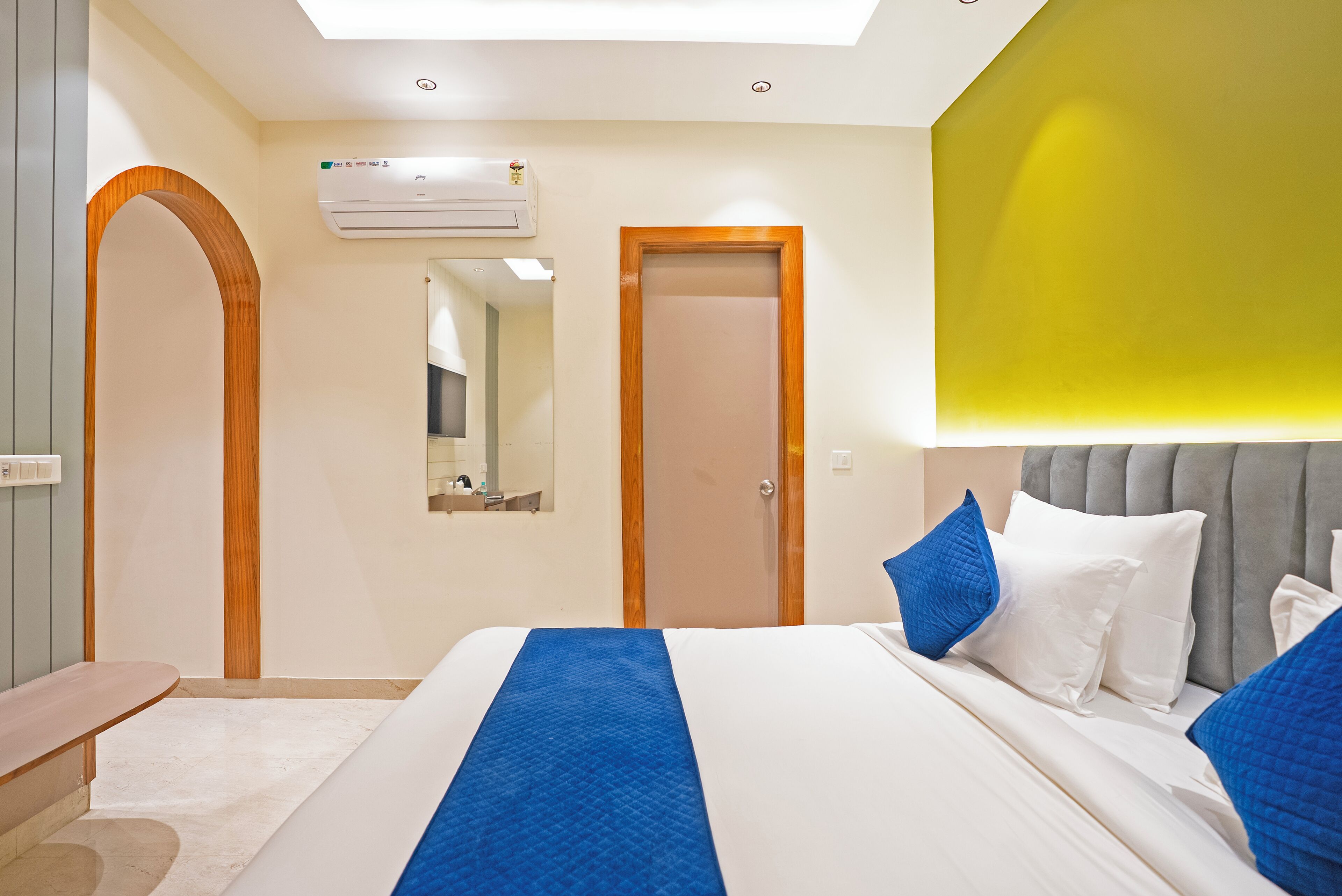 Una habitación de hotel con una cama grande, un espejo, un equipo de aire acondicionado y una puerta.