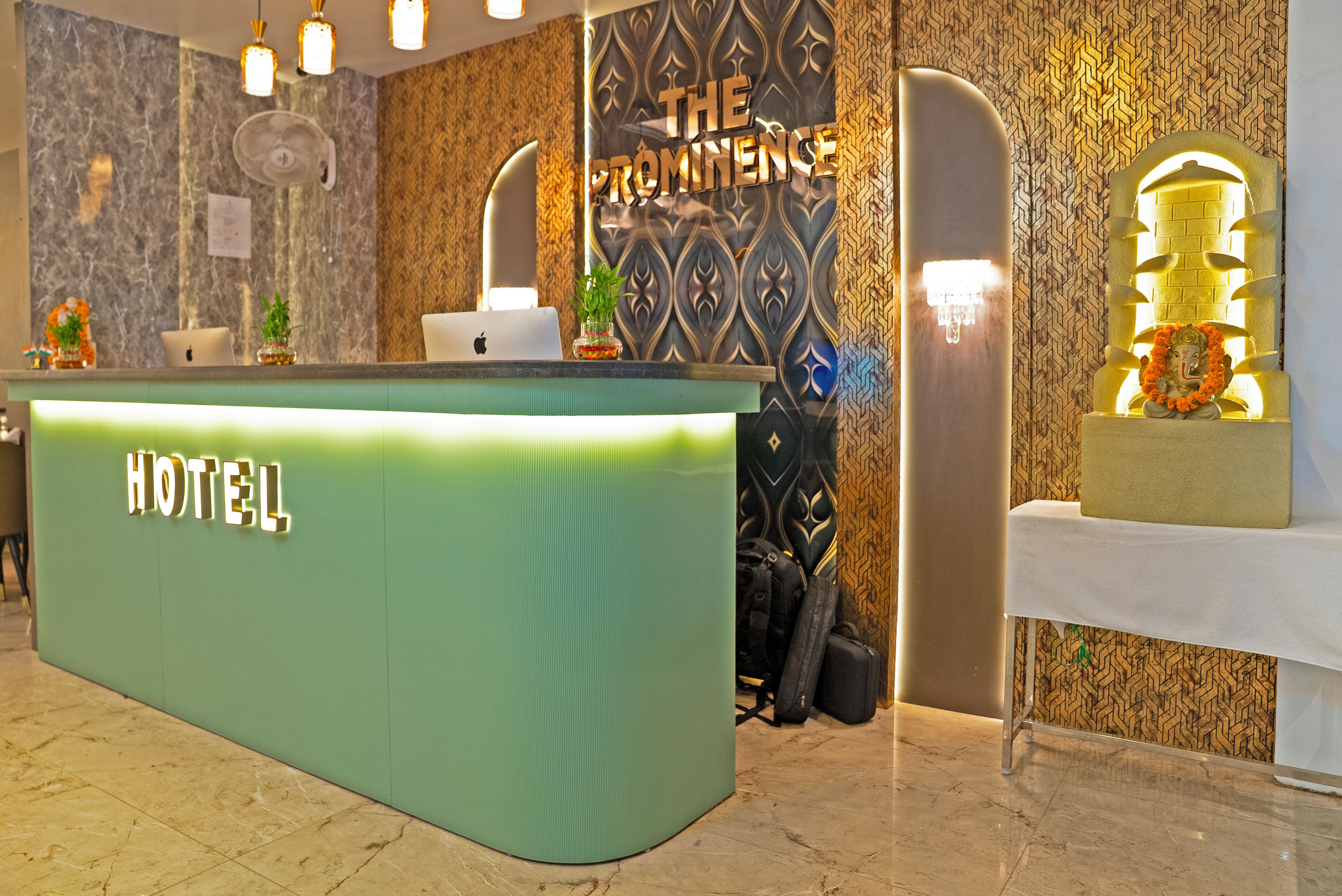 Un mostrador de recepción de hotel con una superficie verde, un cartel que dice "HOTEL" y una pared decorativa con un diseño geométrico.