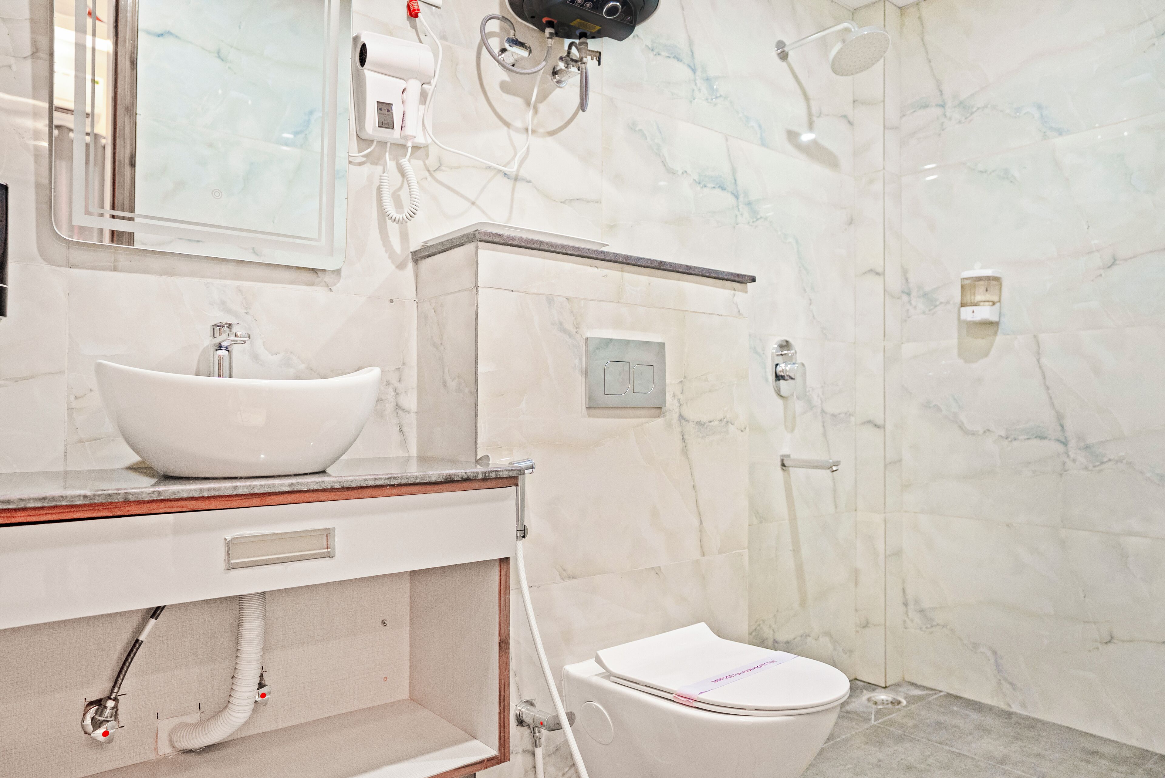 A bathroom with a white sink, mirror, and toilet.