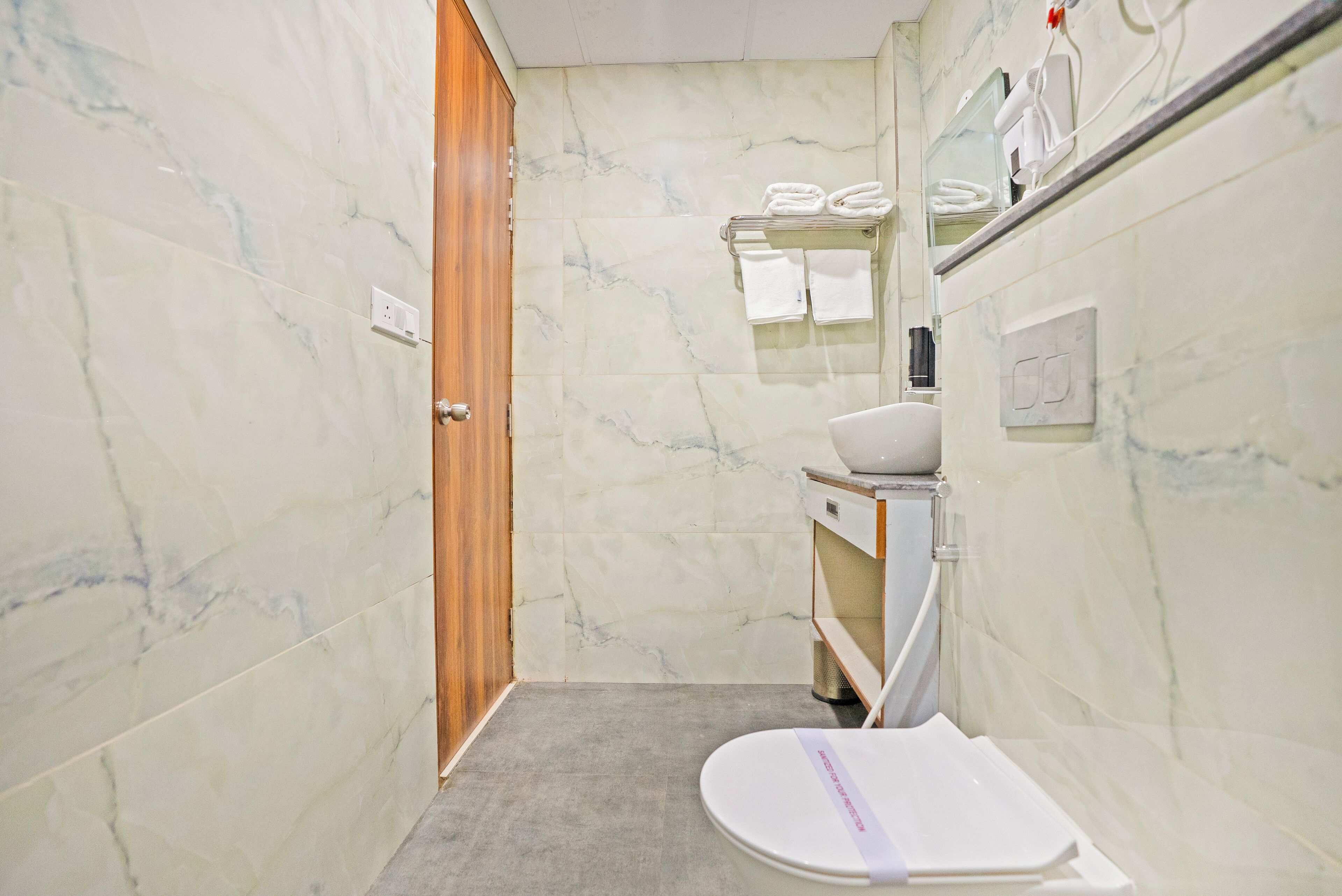 A bathroom with a toilet, a sink, and a mirror.