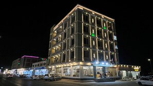 Un hotel de varios pisos con ventanas iluminadas y un restaurante en la planta baja.