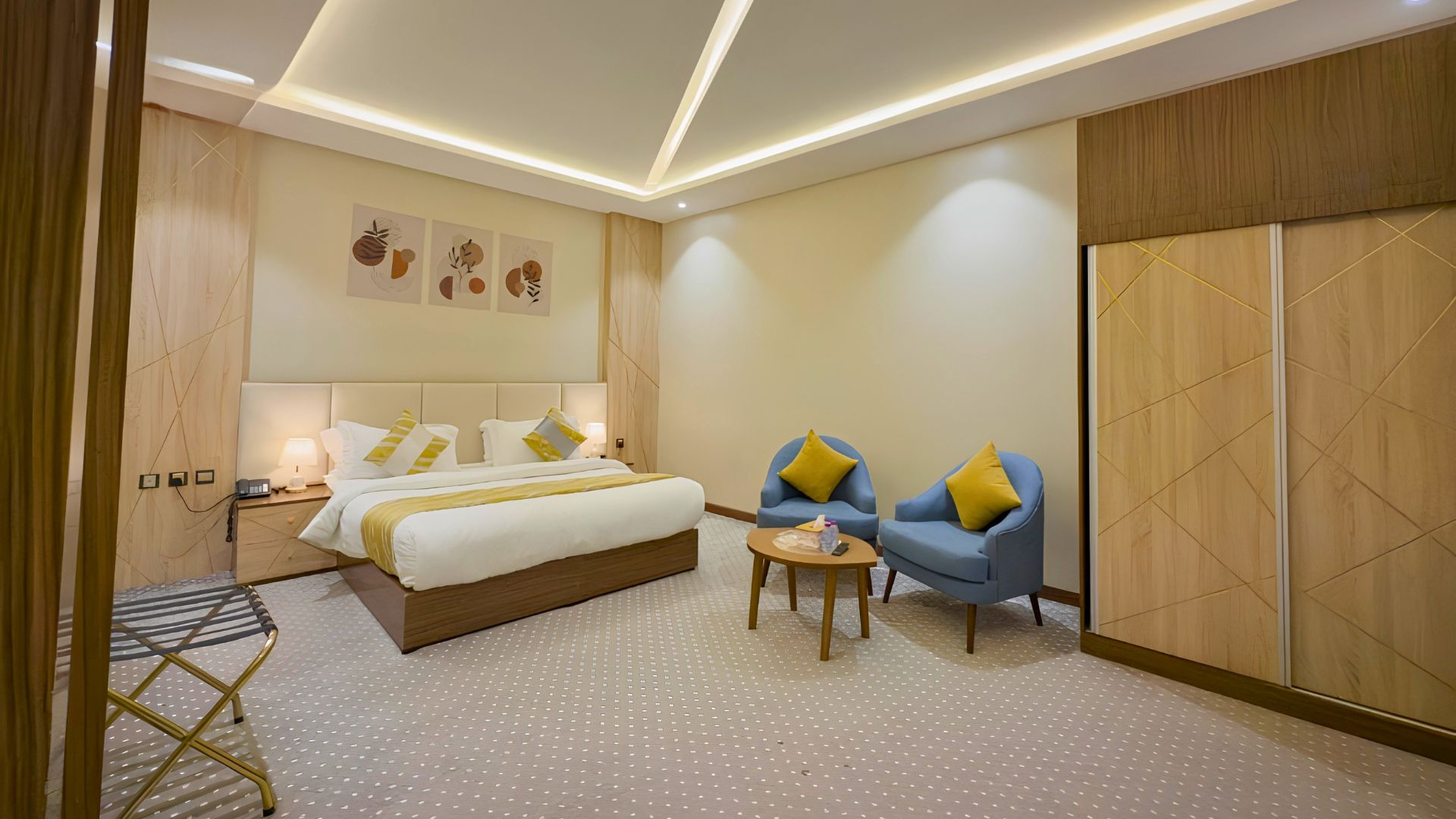 A hotel room with a bed, two armchairs, a small table, and a wardrobe.