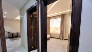 A hotel room with a bed, a desk, and a window with curtains. - AL Ewan Pro Serviced Apartments (Al Kharj)