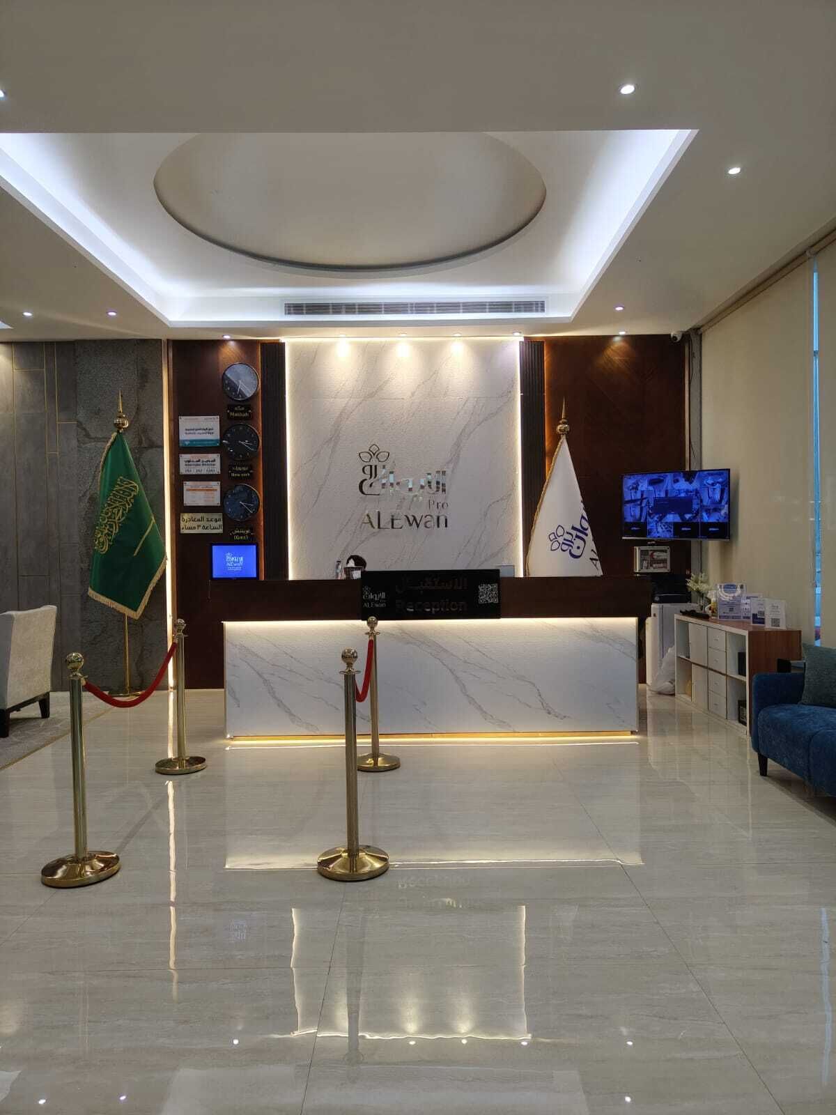 A hotel reception area with a marble counter, a flag, a reception desk, a television, and a blue sofa.