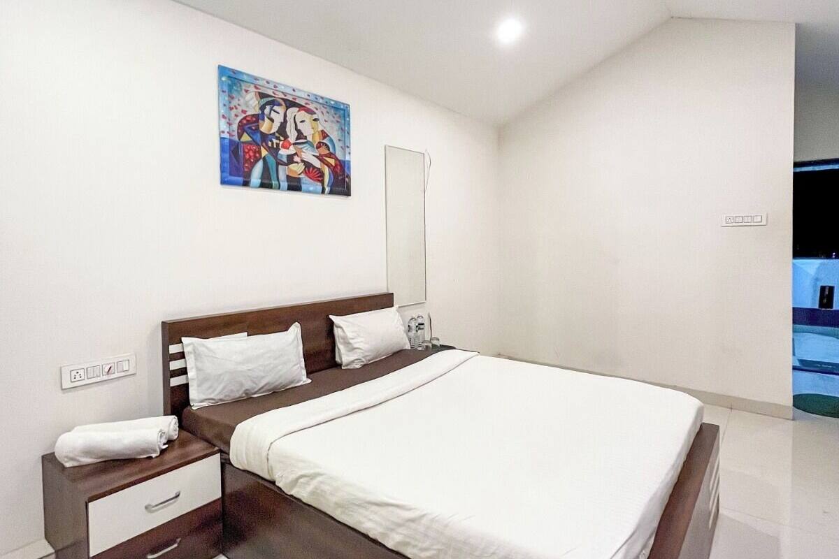 A modern bedroom with a large bed, a nightstand, a bedside table, and a ceiling fan.